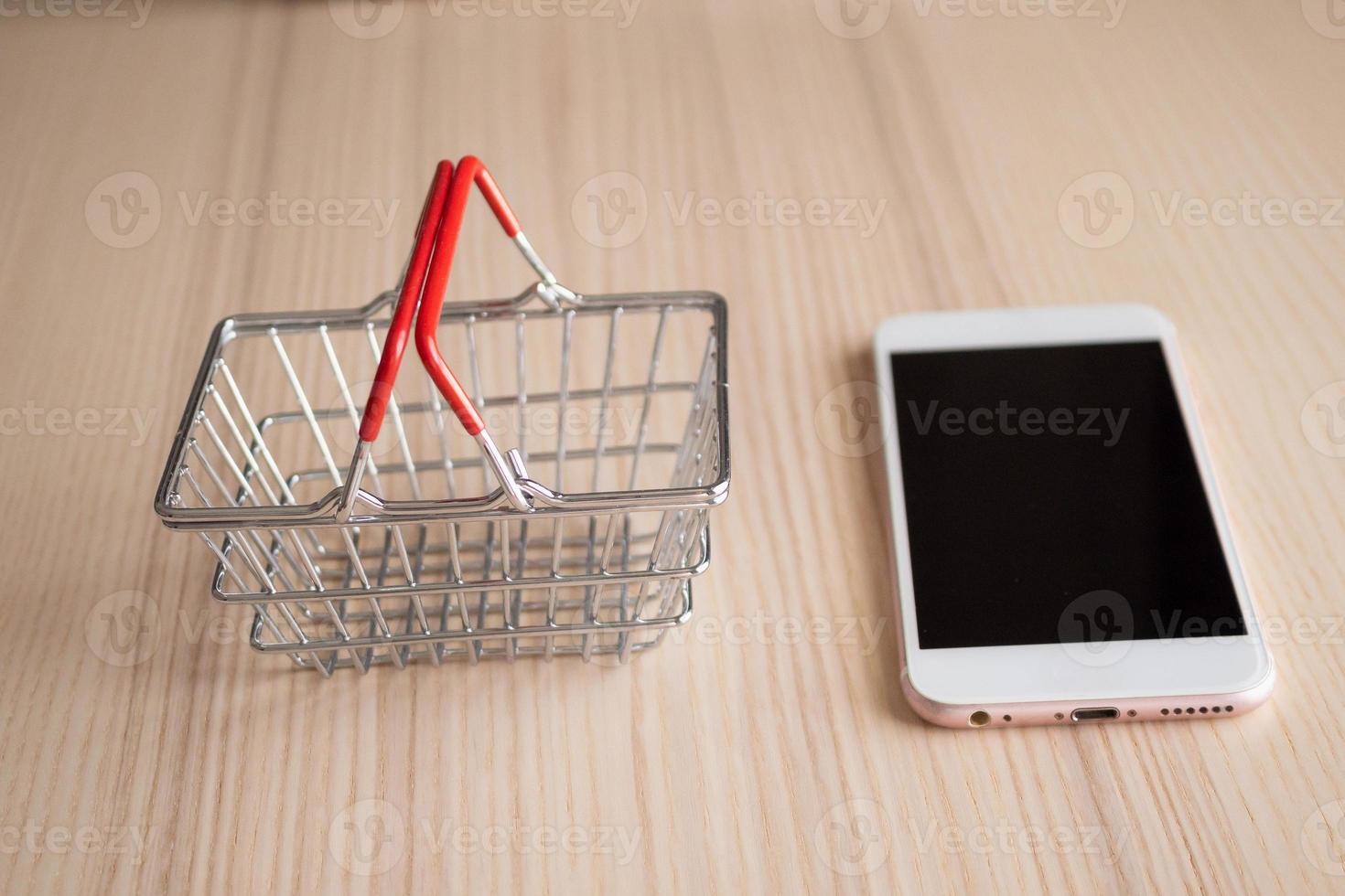 téléphone mobile avec panier sur fond de table en bois shopping concept en ligne photo