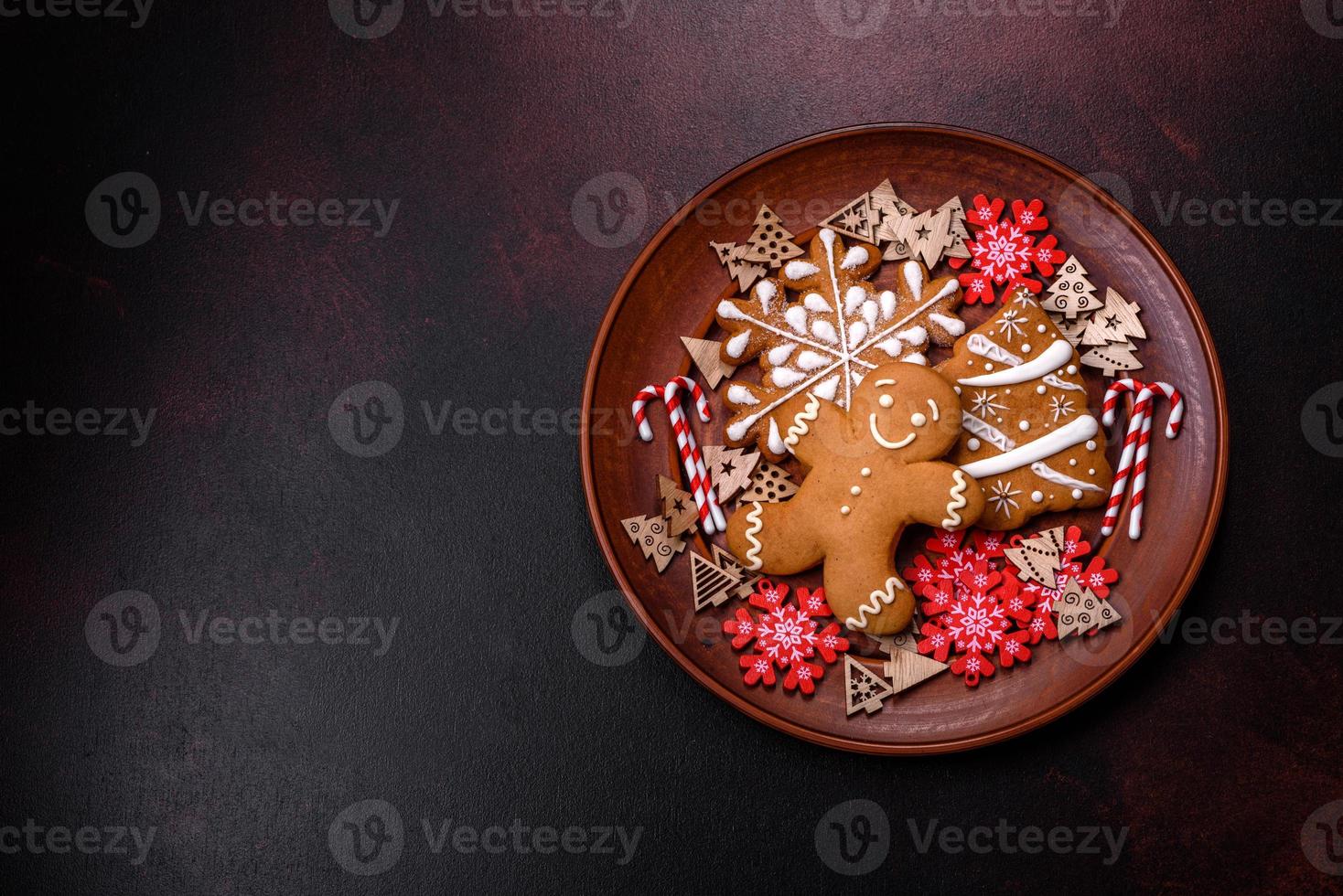 beau pain d'épice sur une plaque en céramique marron avec des décorations d'arbre de noël sur un fond de béton foncé photo