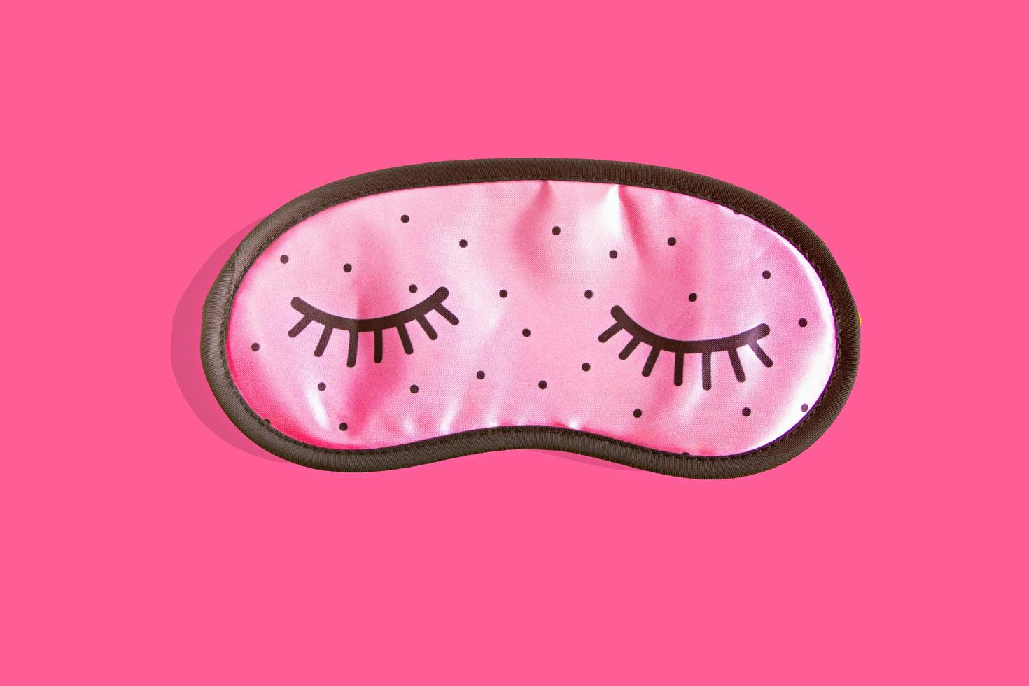 accessoires de masque de sommeil rose pour filles et jeunes femmes aux yeux fermés sur fond rose. vue de dessus, mise à plat. concept de protection oculaire pour de bons rêves et dormir. photo