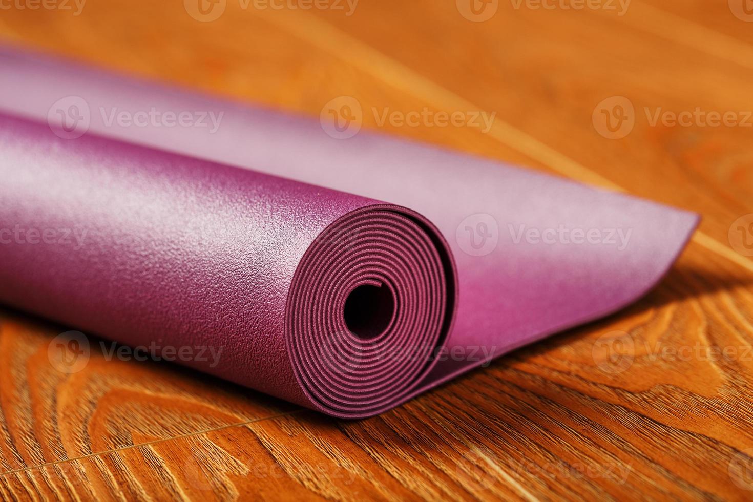 un tapis de yoga de couleur lilas est étalé en rouleau sur le parquet. photo