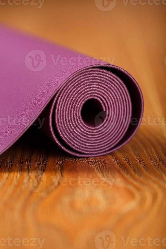 un tapis de yoga de couleur lilas est étalé en rouleau sur le parquet. photo