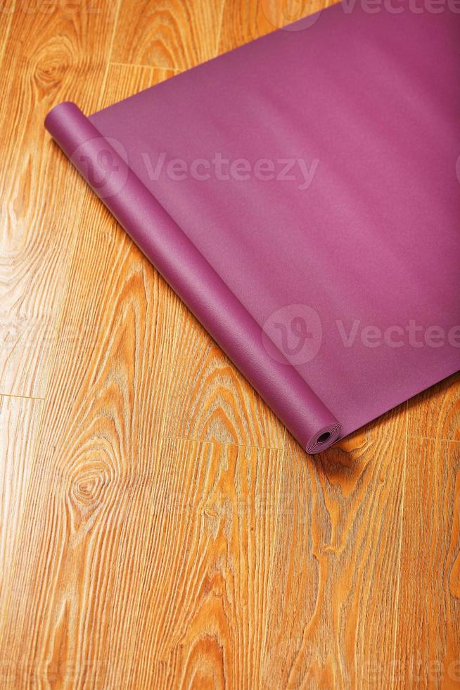 un tapis de yoga lilas est tordu sur le parquet. photo