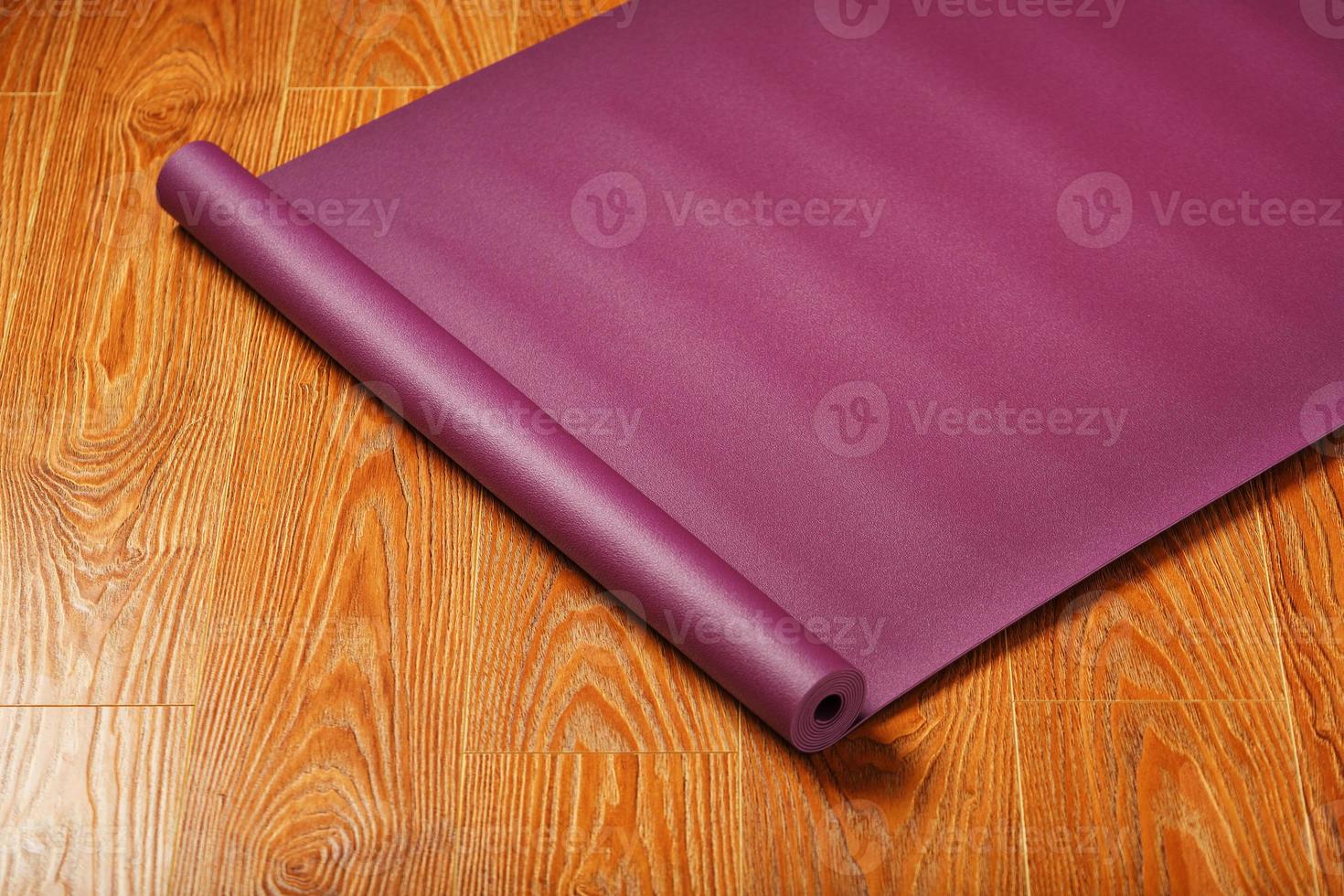 un tapis de yoga de couleur lilas est étalé en rouleau sur le parquet. photo