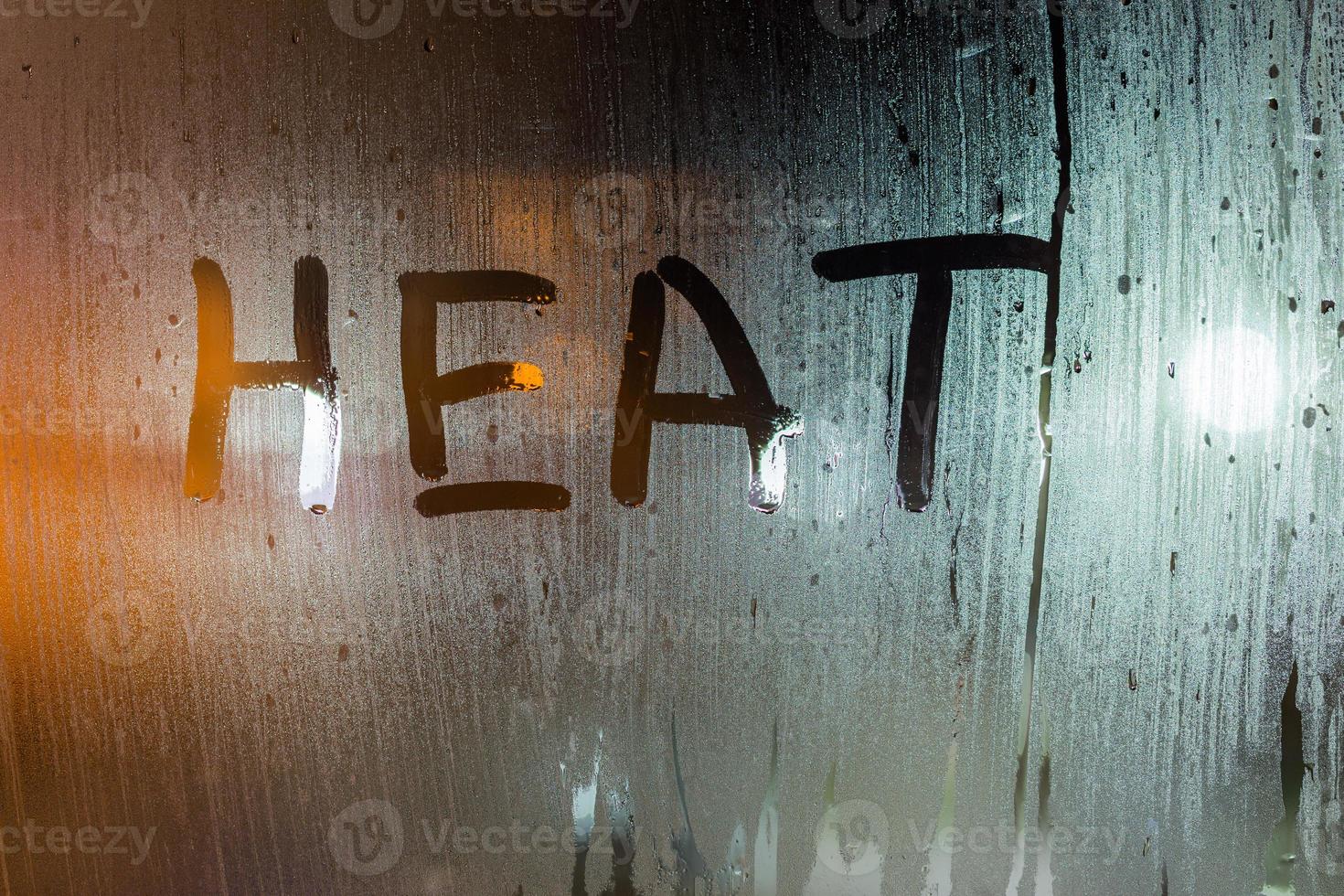 Le mot chaleur écrit sur la vitre humide de la nuit en gros plan avec un arrière-plan flou photo