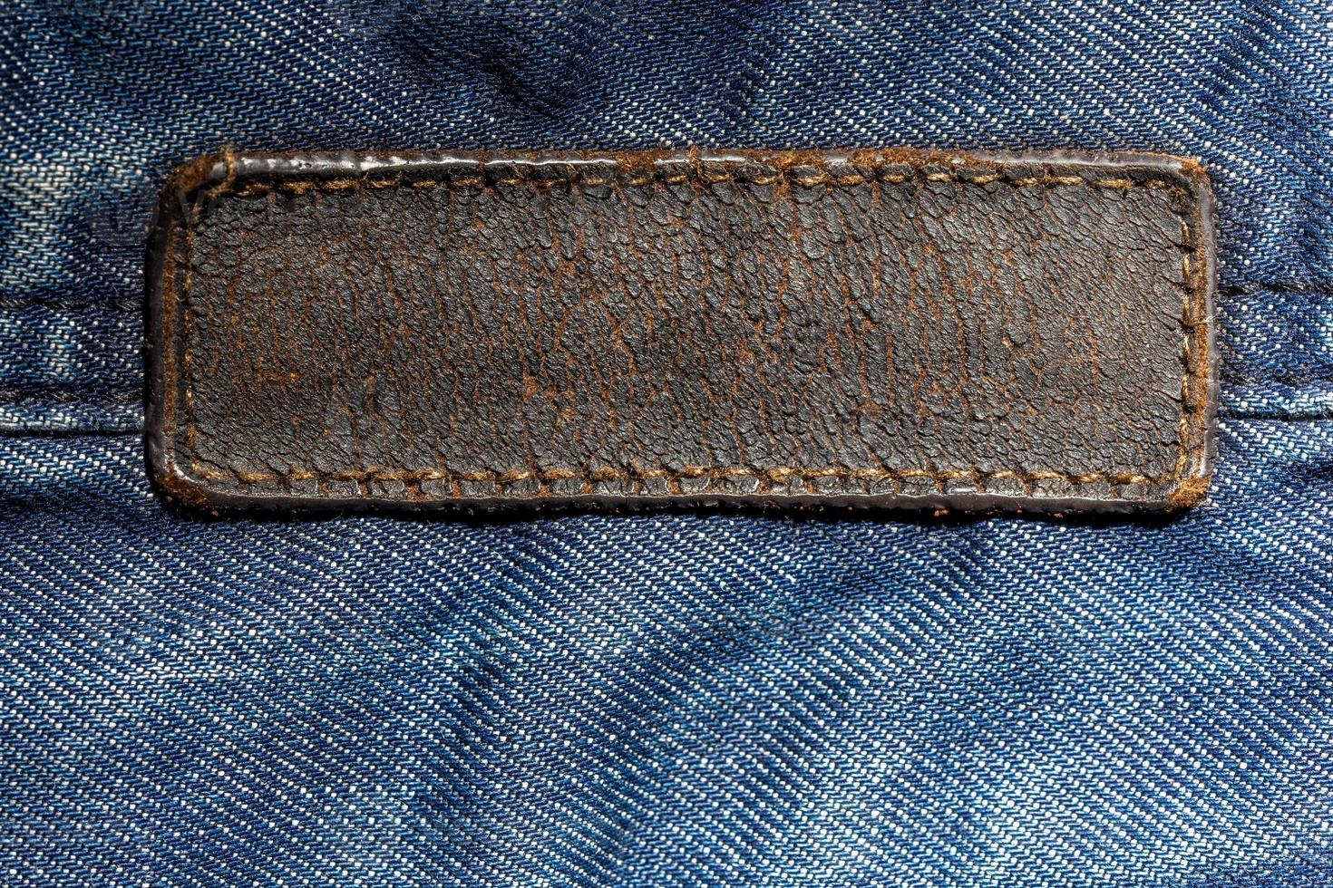 ancienne étiquette en cuir vierge sur tissu denim bleu - gros plan avec mise au point sélective. étiquette longue photo