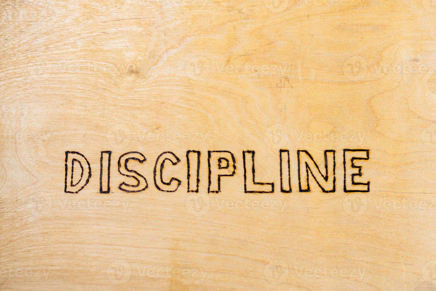 mot discipline manuscrite avec poêle à bois sur une surface plane en bois - directement au-dessus de la vue normale photo
