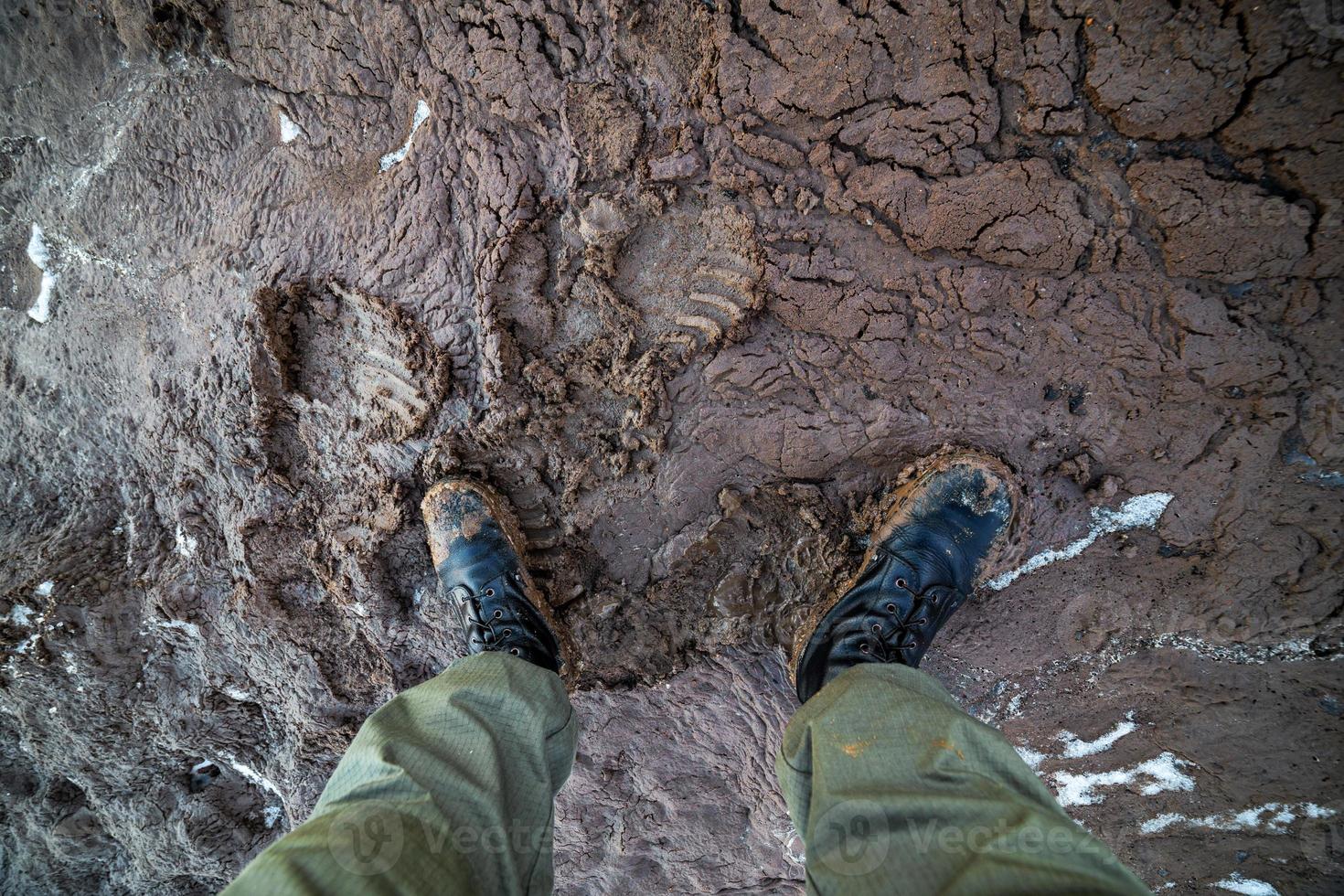jambes dans des bottes de l'armée dans la boue humide vue de dessus en gros plan avec mise au point sélective à la lumière du jour photo