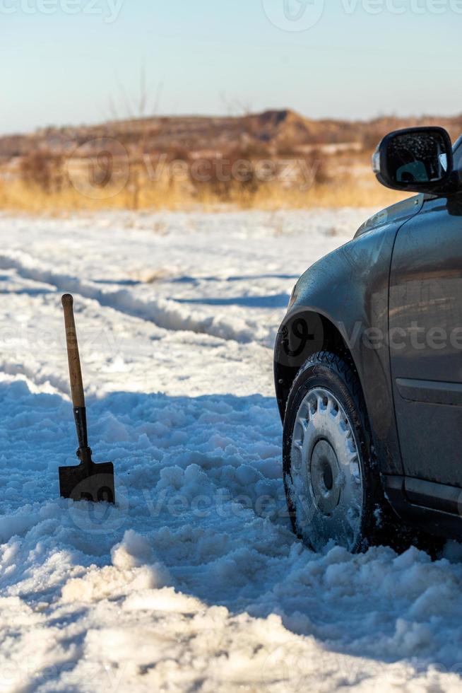 voiture coincée dans la neige tout-terrain à la lumière du jour avec pelle  et mise au point sélective 12631510 Photo de stock chez Vecteezy