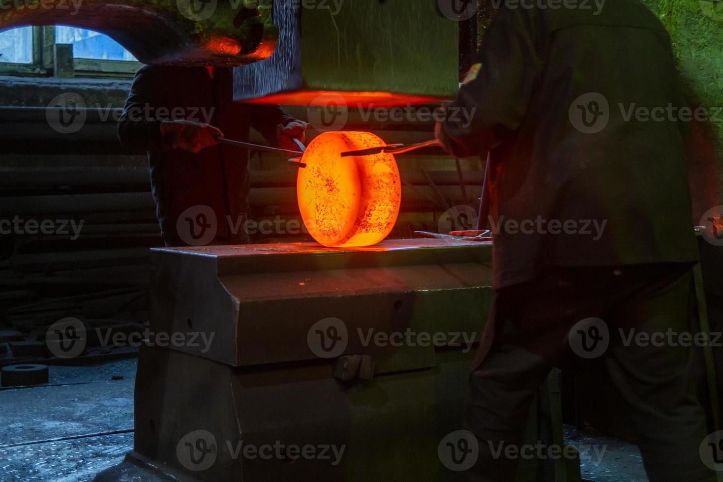 photo en gros plan du processus de forgeage manuel de l'acier chaud avec une grande machine à marteaux mécaniques