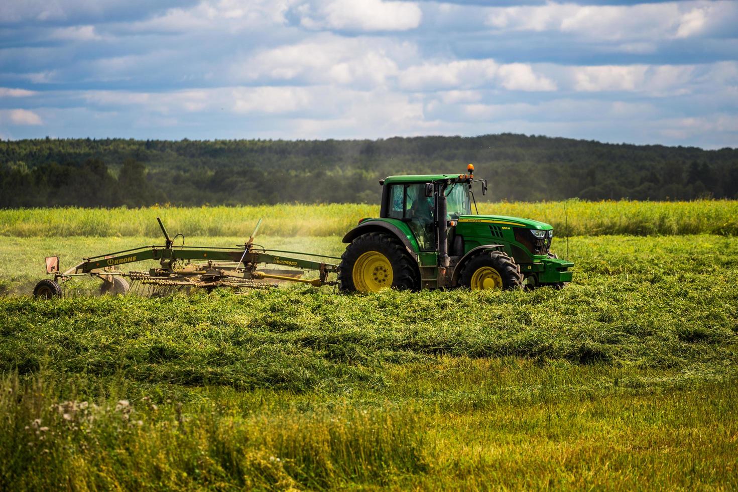 tula, russie 30 juillet 2019 tracteur de fenaison vert sur le terrain d'été avant la tempête - prise de vue au téléobjectif avec mise au point sélective photo