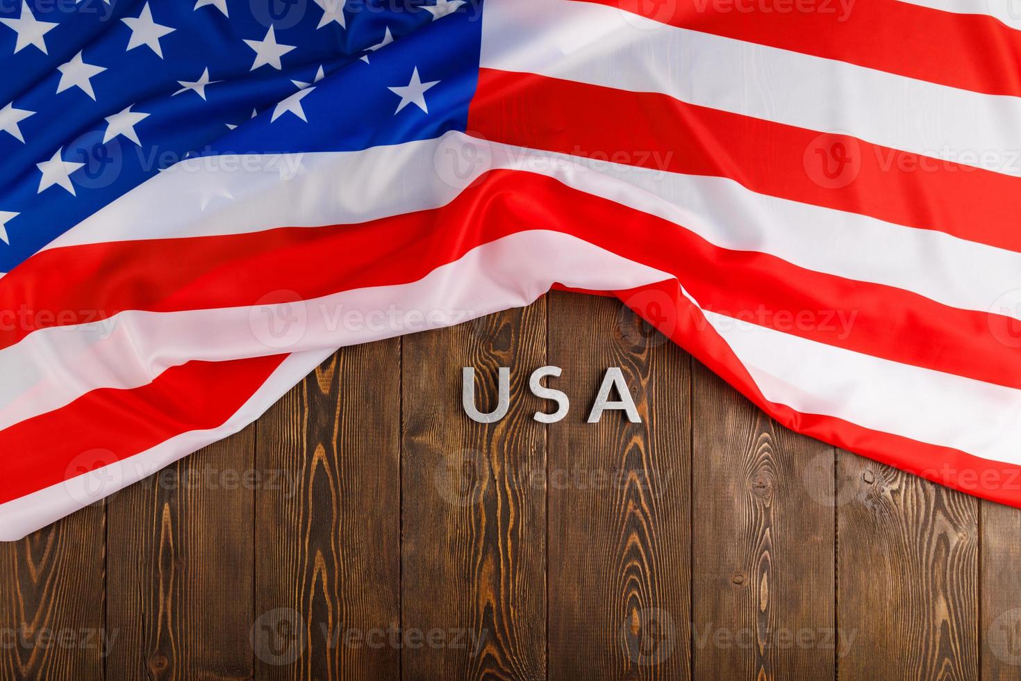 Le mot usa posé avec des lettres en métal argenté sur la surface de la planche de bois sous le drapeau froissé des États-Unis d'Amérique photo