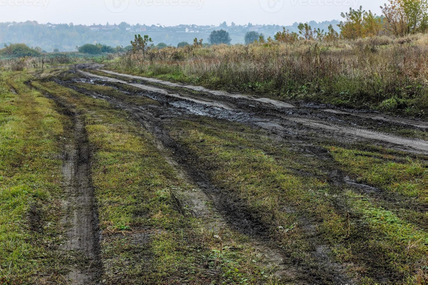 paysage rustique matin brumeux d'automne avec chemin de terre au premier plan et petits bâtiments sur la colline en arrière-plan photo