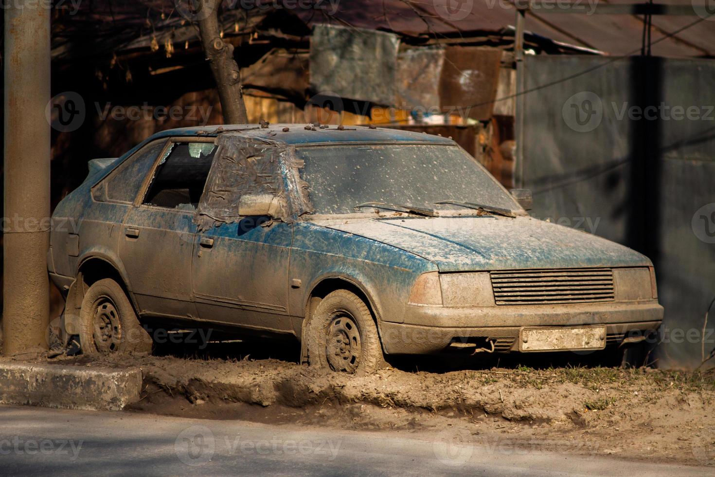 vieille voiture abandonnée sale sur sideroad avec une épaisse couche de boue et une fenêtre cassée à la lumière du jour. photo