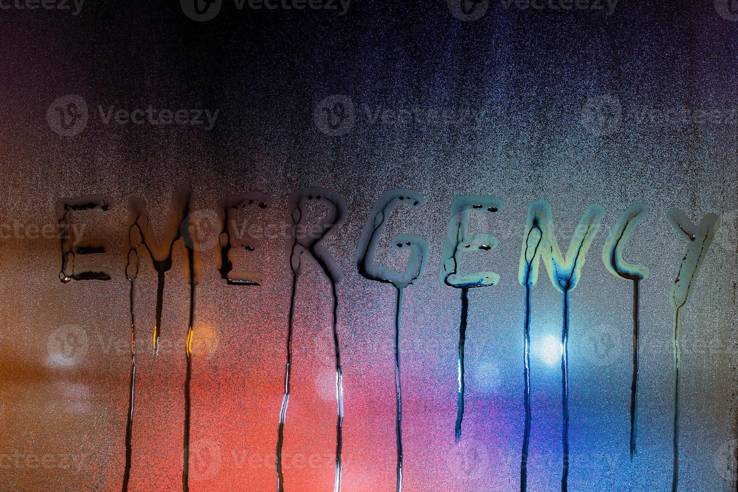 Le mot d'urgence écrit sur la vitre humide de la nuit en gros plan avec un arrière-plan flou photo