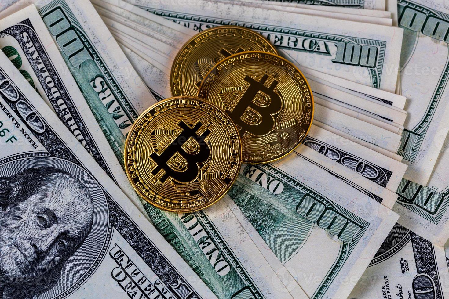 Trois ménés bitcoin sur papier fond de billets en dollars américains photo
