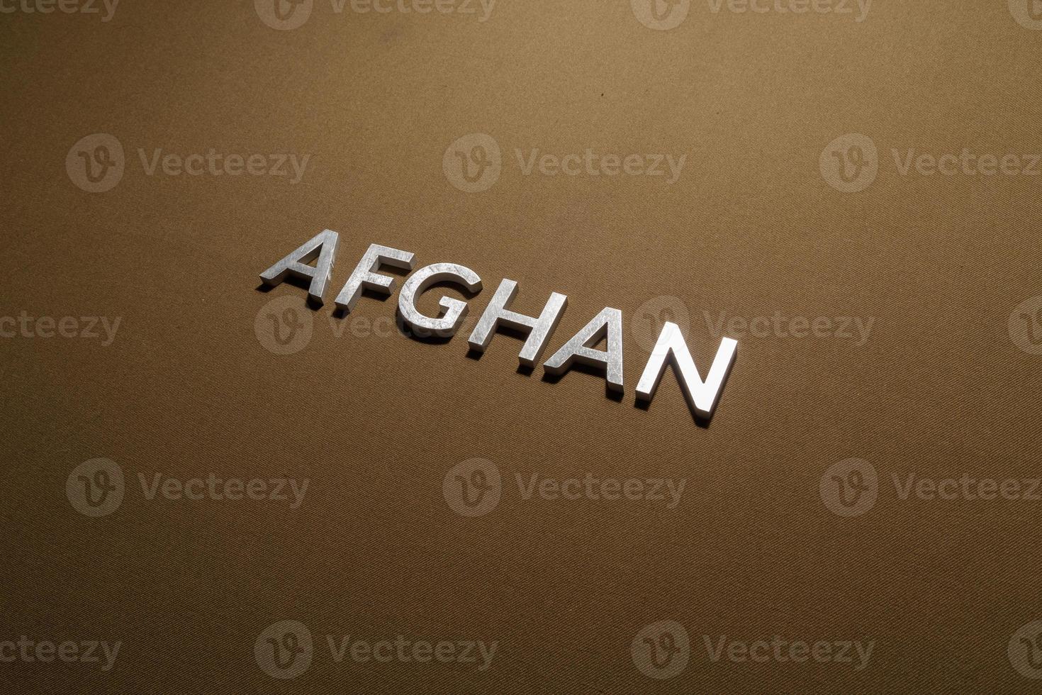 le mot afghan posé avec des lettres en métal argenté sur un tissu en toile kaki beige rugueux photo