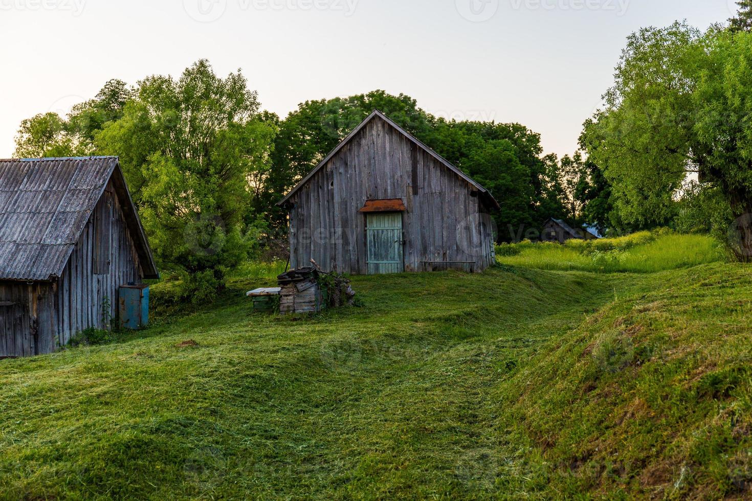 Anciennes granges en bois sur cour avec pelouse tondue au soir d'été photo