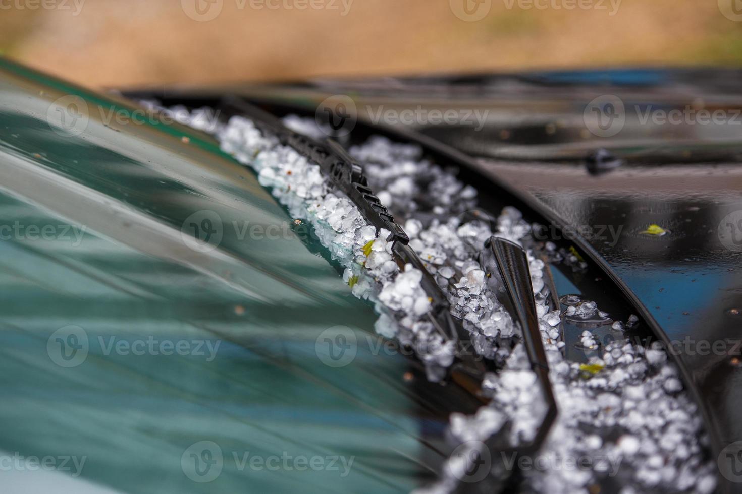 Petites boules de glace de grêle sur capot de voiture noir après une forte tempête estivale photo