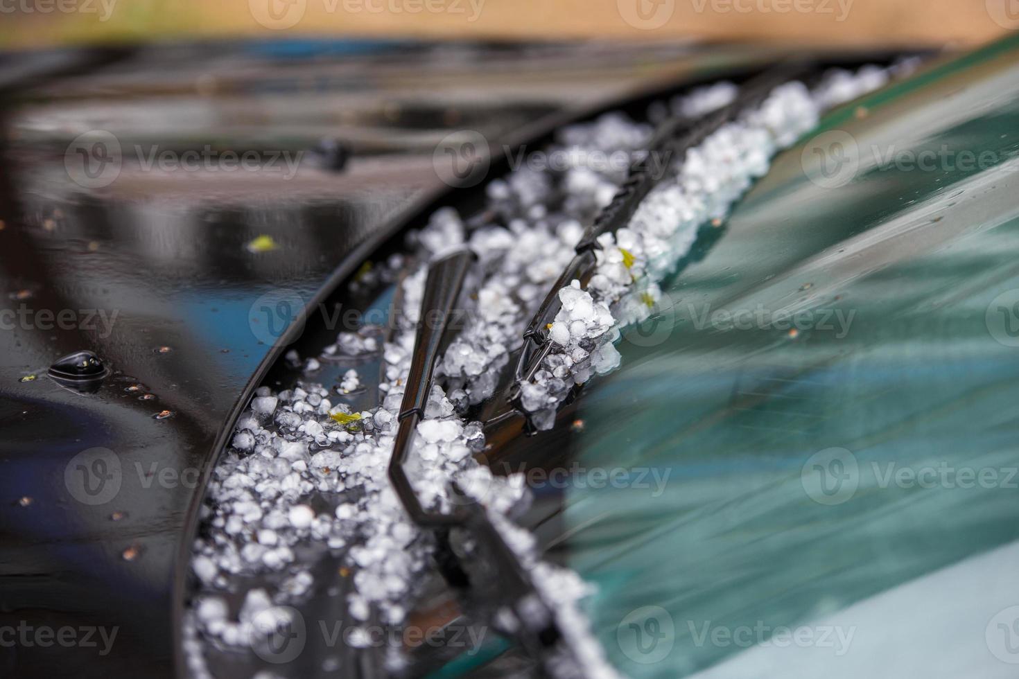 Petites boules de glace de grêle sur capot de voiture noir après une forte tempête estivale photo