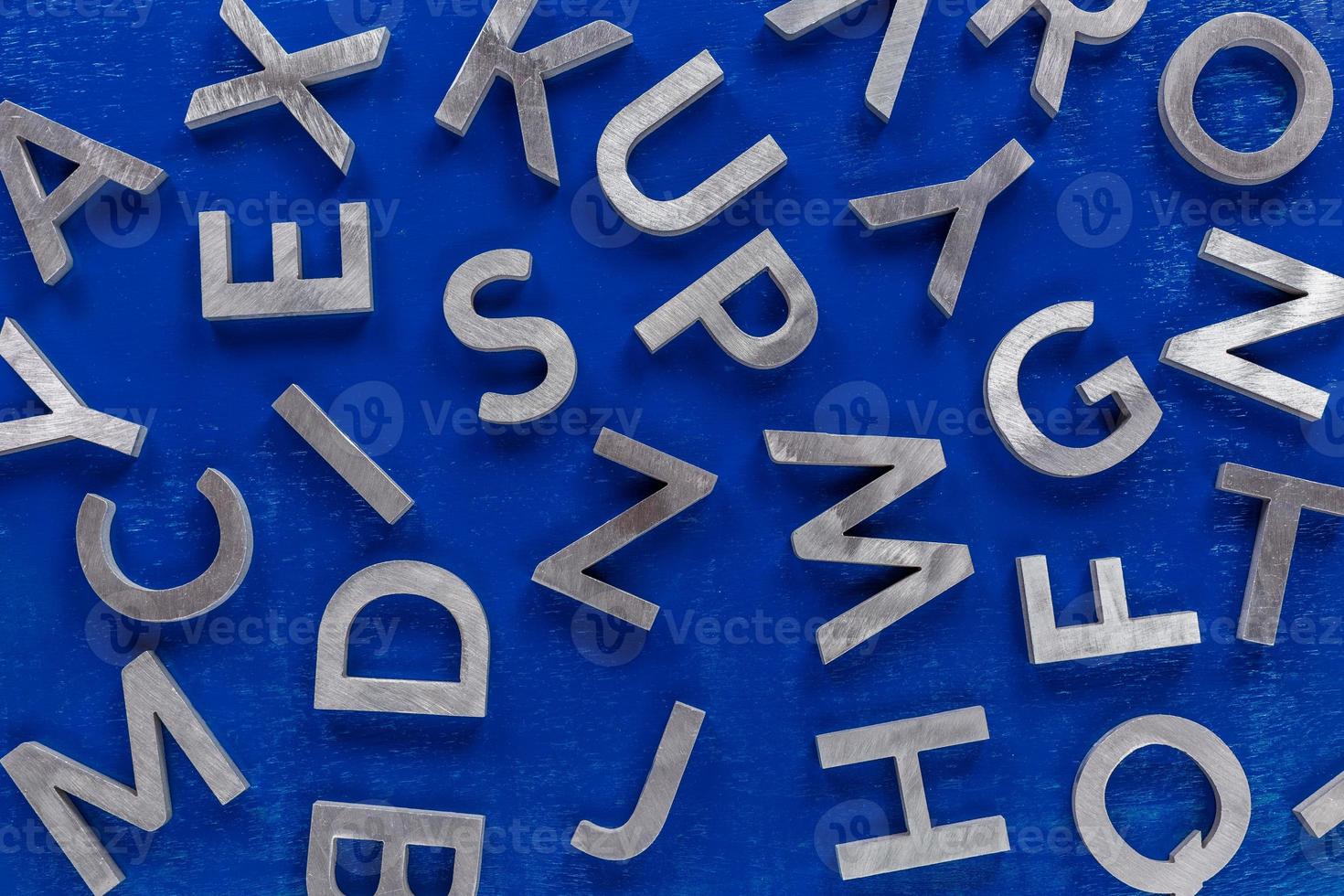 abstrait plat de caractères de l'alphabet anglais en métal argenté sur fond bleu. photo