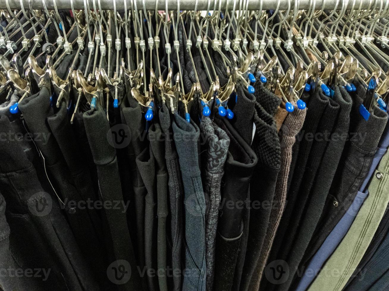 une rangée de cintres avec un pantalon bon marché dans le magasin d'un marché. gros plan avec mise au point sélective. photo