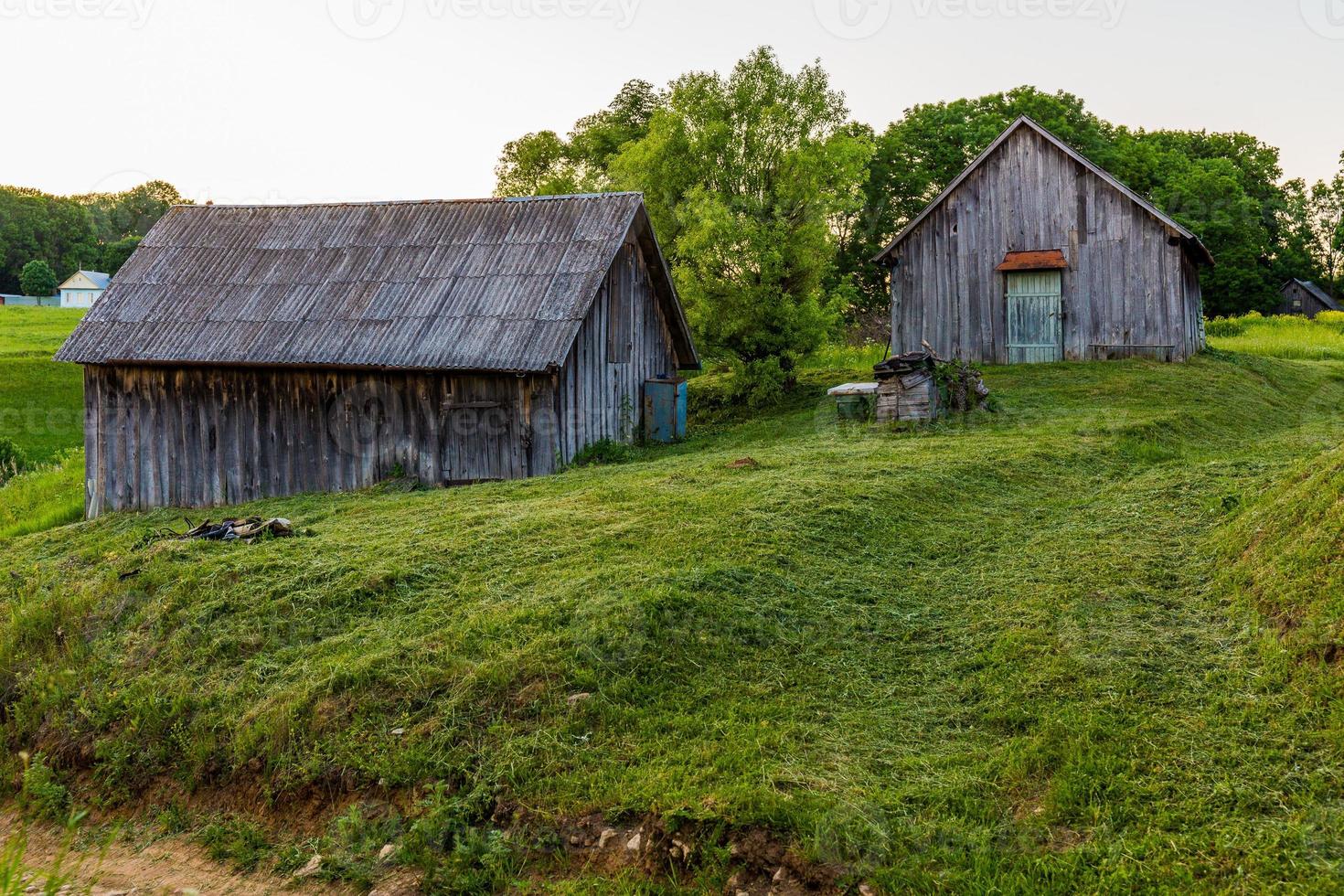 Anciennes granges en bois sur cour avec pelouse tondue au soir d'été photo