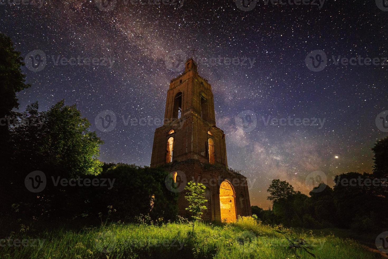 ruine du clocher de nuit dans la forêt la nuit étoilée avec lumière interne photo