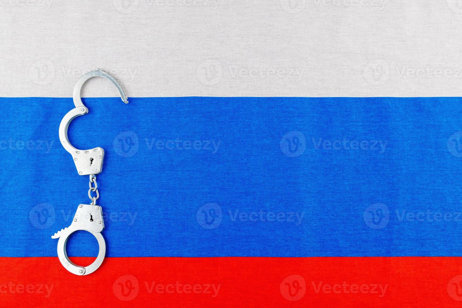 menottes ouvertes en métal argenté posées sur fond plein cadre du drapeau russe photo