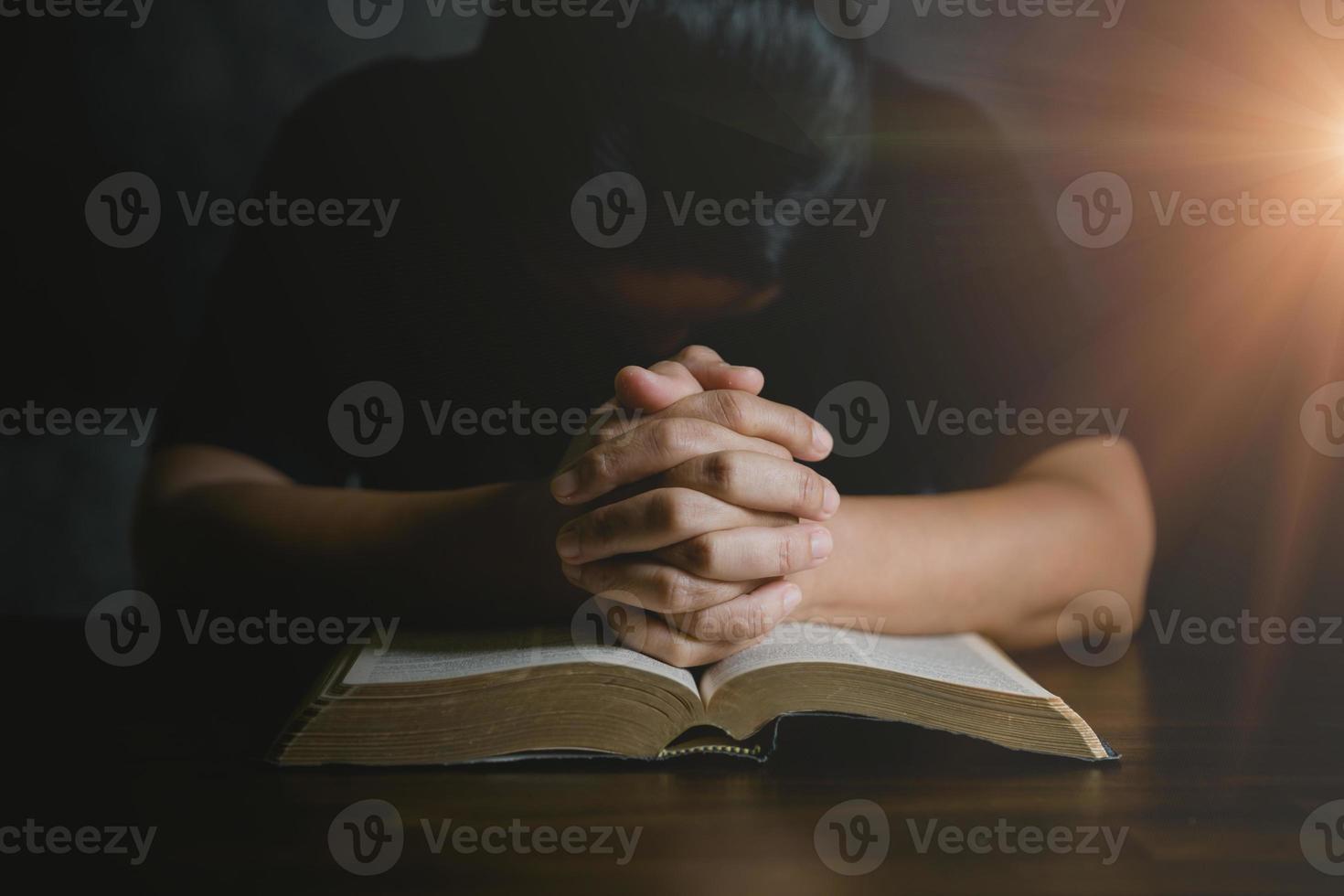 main de personne de prière sur fond noir. une femme catholique chrétienne prie Dieu dans le noir à l'église. fille croit et foi en jésus christ. la religion du christ et le christianisme adorent ou prient le concept. photo