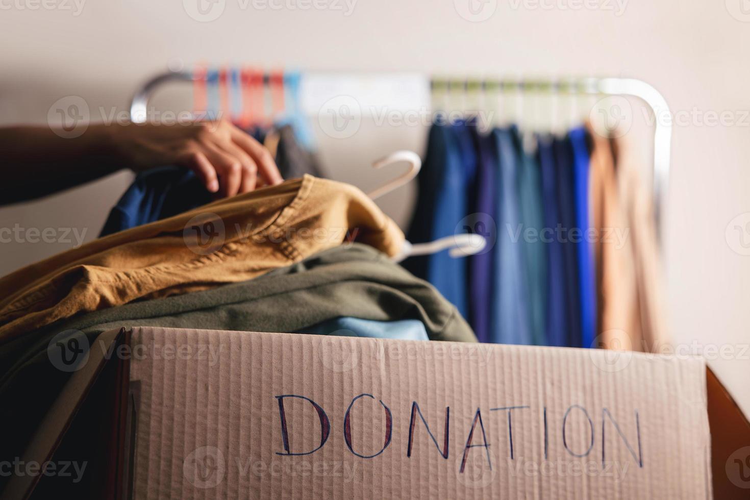 notion de don. préparer de vieux vêtements usagés à partir d'un porte-armoire dans une boîte de dons. se concentrer sur le texte photo