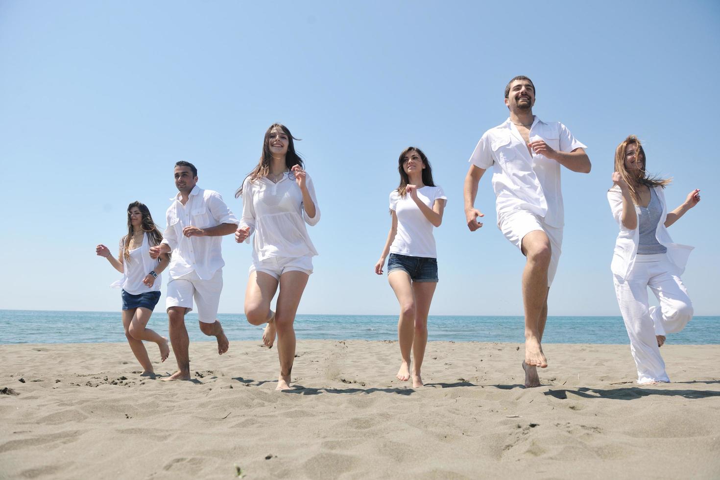 groupe de personnes heureuses s'amuser et courir sur la plage photo