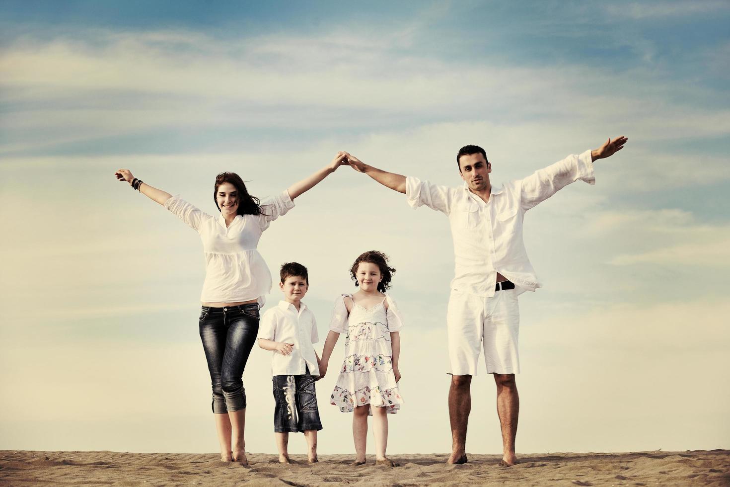 famille sur la plage montrant le signe de la maison photo