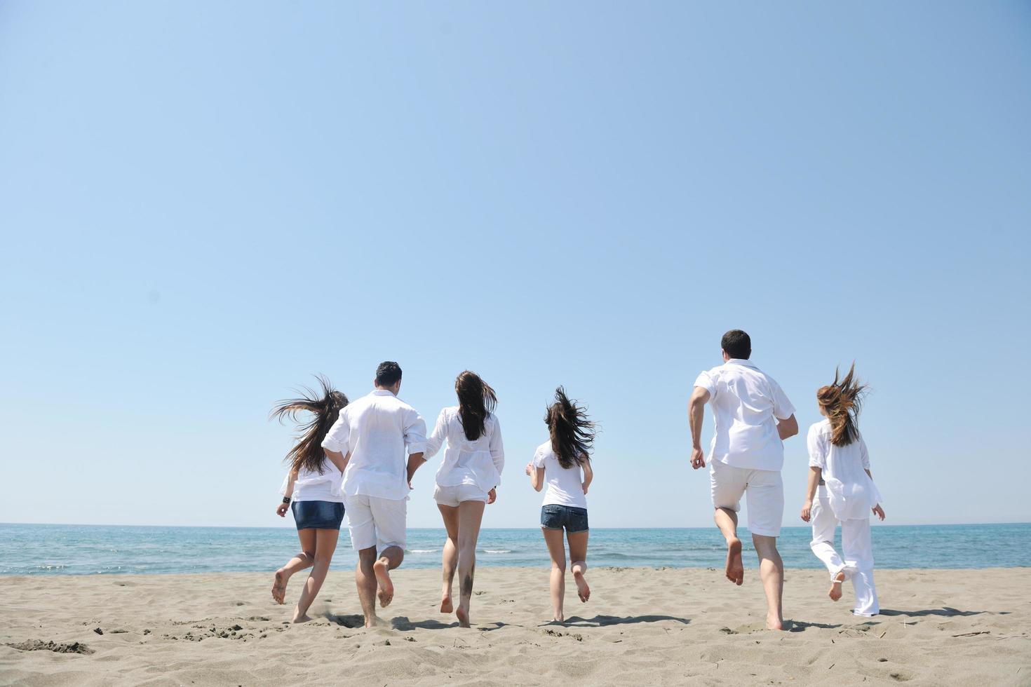 groupe de personnes heureuses s'amuser et courir sur la plage photo