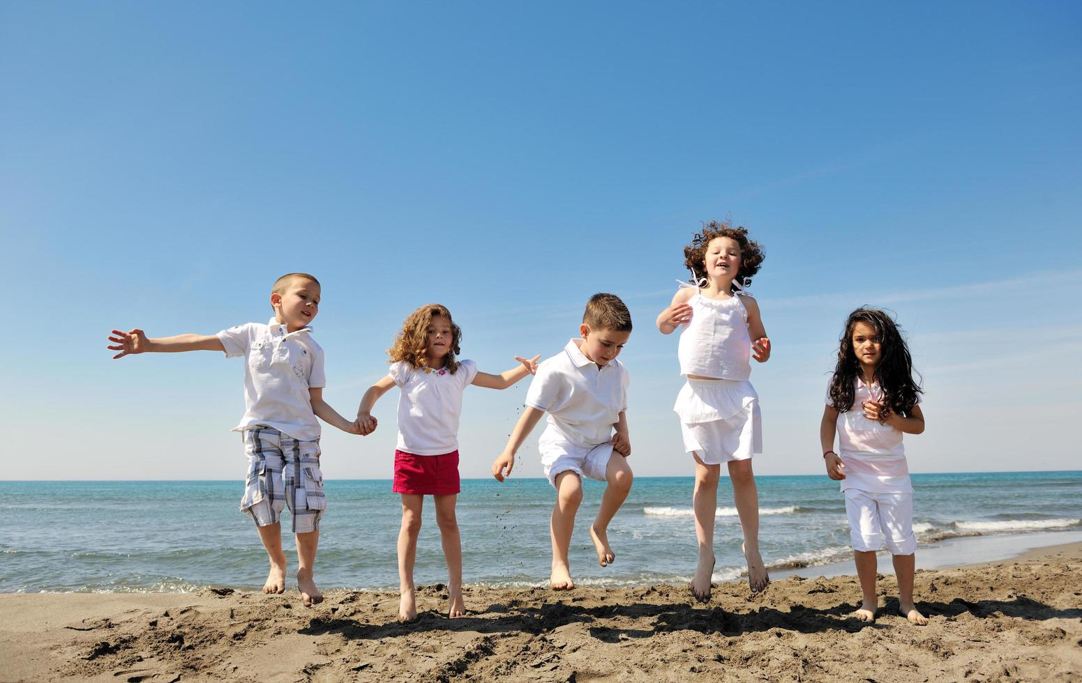 groupe d'enfants heureux jouant sur la plage photo