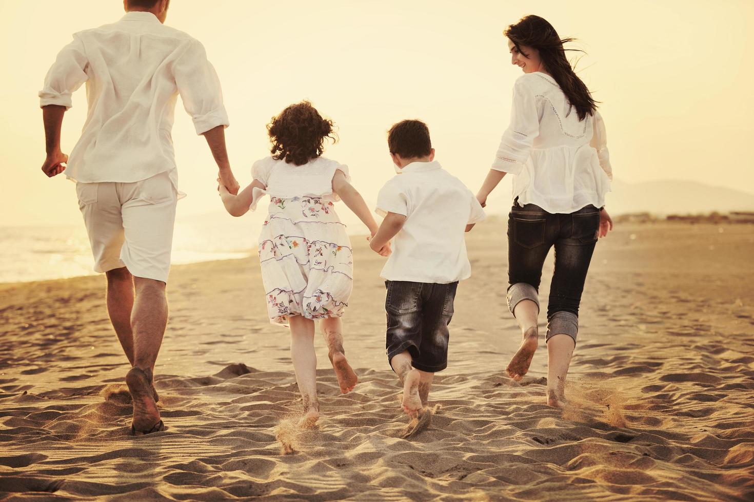 jeune famille heureuse s'amuser sur la plage au coucher du soleil photo