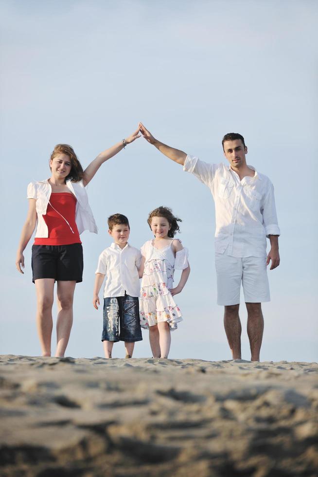 famille sur la plage montrant le signe de la maison photo