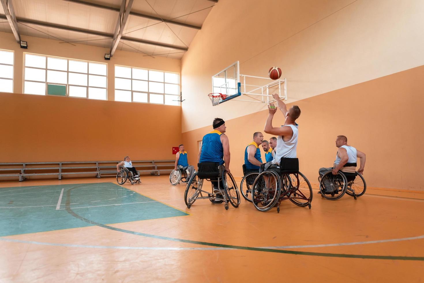 Anciens combattants handicapés de guerre mixtes et équipes de basket-ball d'âge en fauteuil roulant jouant un match d'entraînement dans une salle de sport. concept de réadaptation et d'inclusion des personnes handicapées photo