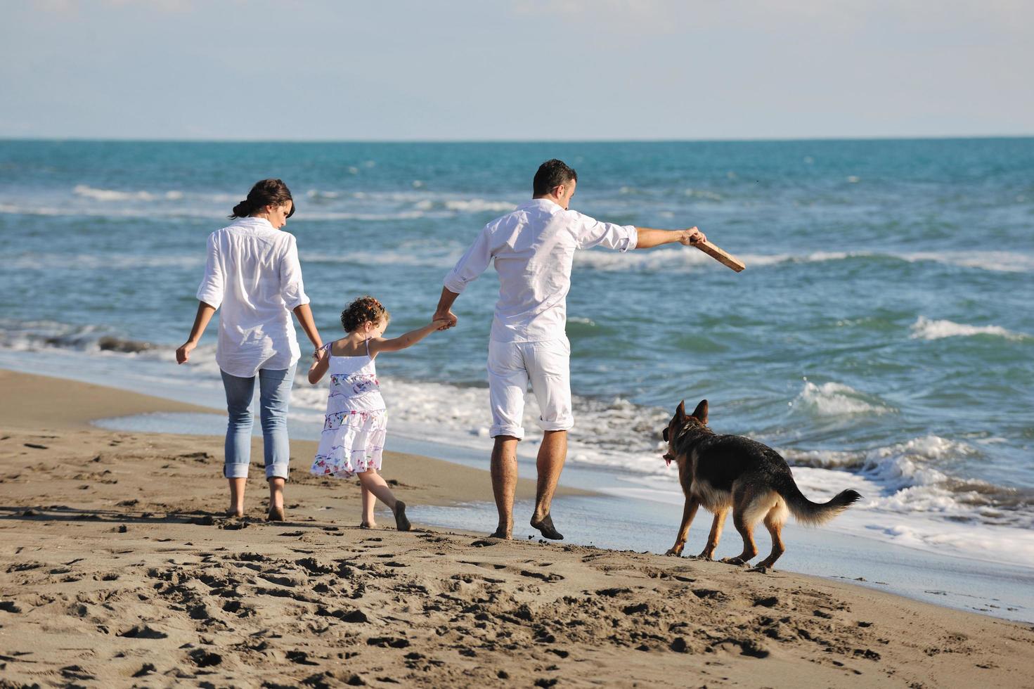 famille heureuse jouant avec un chien sur la plage photo