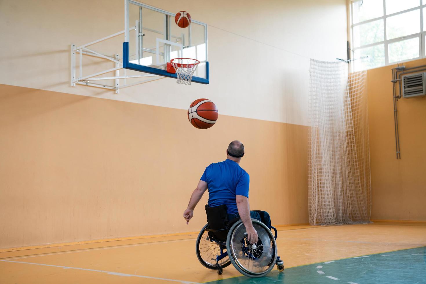 un invalide de guerre en fauteuil roulant s'entraîne avec un ballon dans un club de basket-ball en formation avec des équipements sportifs professionnels pour handicapés. le concept de sport pour les personnes handicapées photo