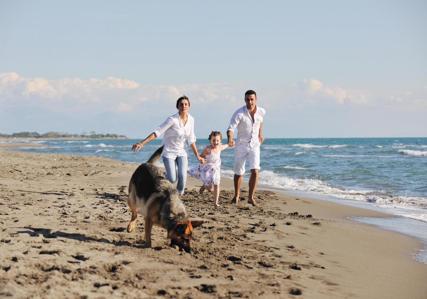 famille heureuse jouant avec un chien sur la plage photo