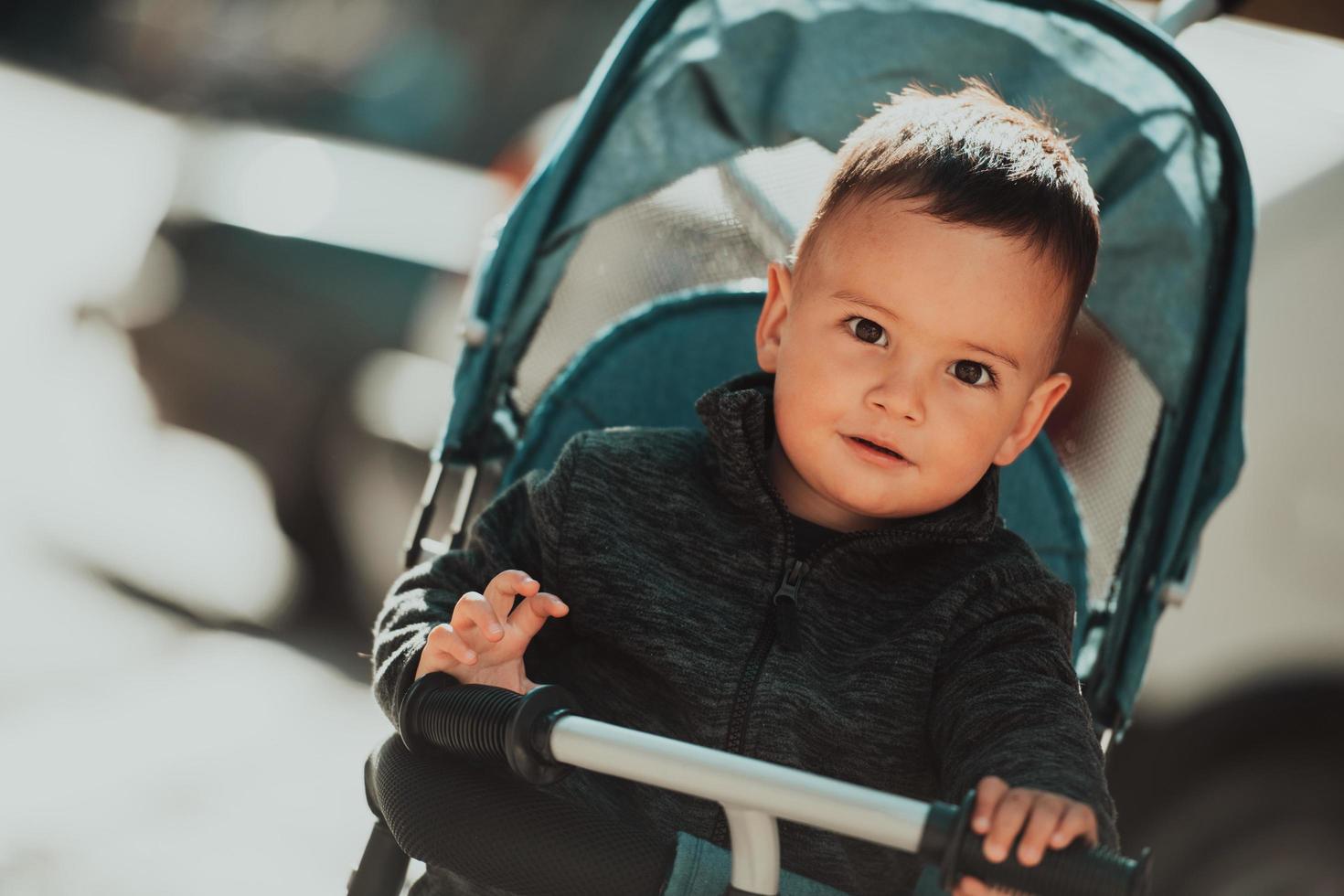 doux petit garçon dans un vélo poussette à l'extérieur. petit enfant dans un landau. enfant en bas âge dans une poussette. promenades printanières avec les enfants. photo