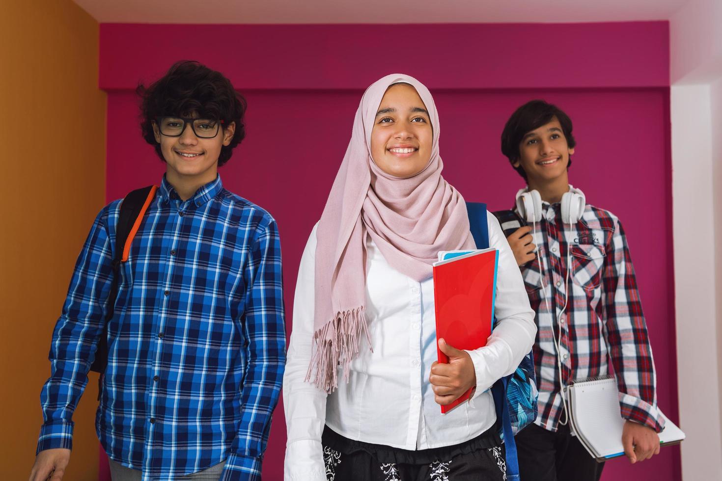 un groupe d'adolescents arabes, une équipe d'étudiants marchant vers l'avenir et retournant à l'école le concept d'un fond rose. le concept d'éducation réussie pour les jeunes. mise au point sélective photo