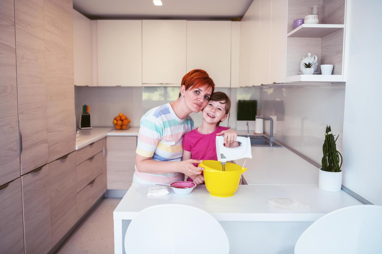 une petite fille amusante jouant avec de la pâte sur ses mains apprenant à pétrir aide une maman adulte dans la cuisine, une petite fille mignonne et heureuse et une maman parent s'amusent à cuisiner des biscuits. photo