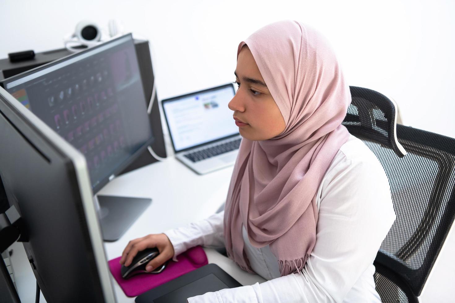 professionnelle créative arabe féminine travaillant au bureau à domicile sur un ordinateur de bureau avec vue de dessus de moniteur à double écran. mise au point sélective photo