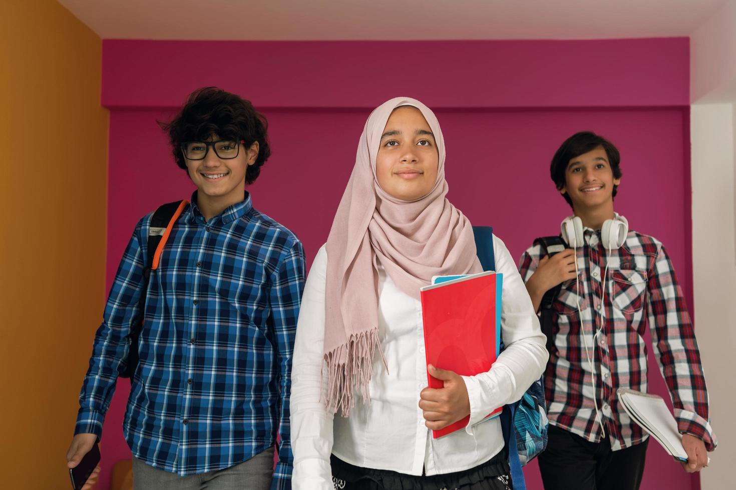 un groupe d'adolescents arabes, une équipe d'étudiants marchant vers l'avenir et retournant à l'école le concept d'un fond rose. le concept d'éducation réussie pour les jeunes. mise au point sélective photo