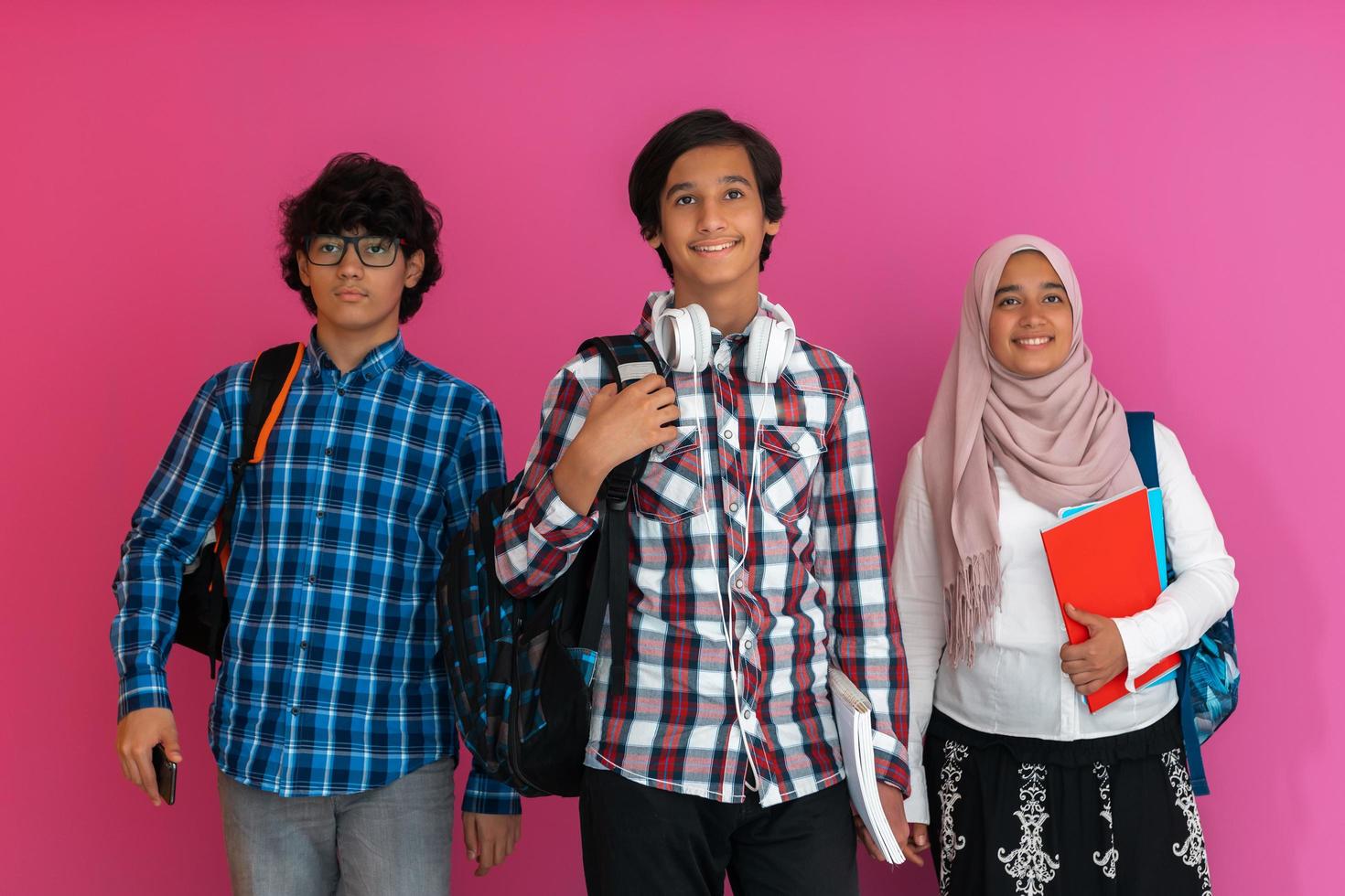 un groupe d'adolescents arabes, une équipe d'étudiants marchant vers l'avenir et retournant à l'école le concept d'un fond rose. le concept d'éducation réussie pour les jeunes. mise au point sélective photo