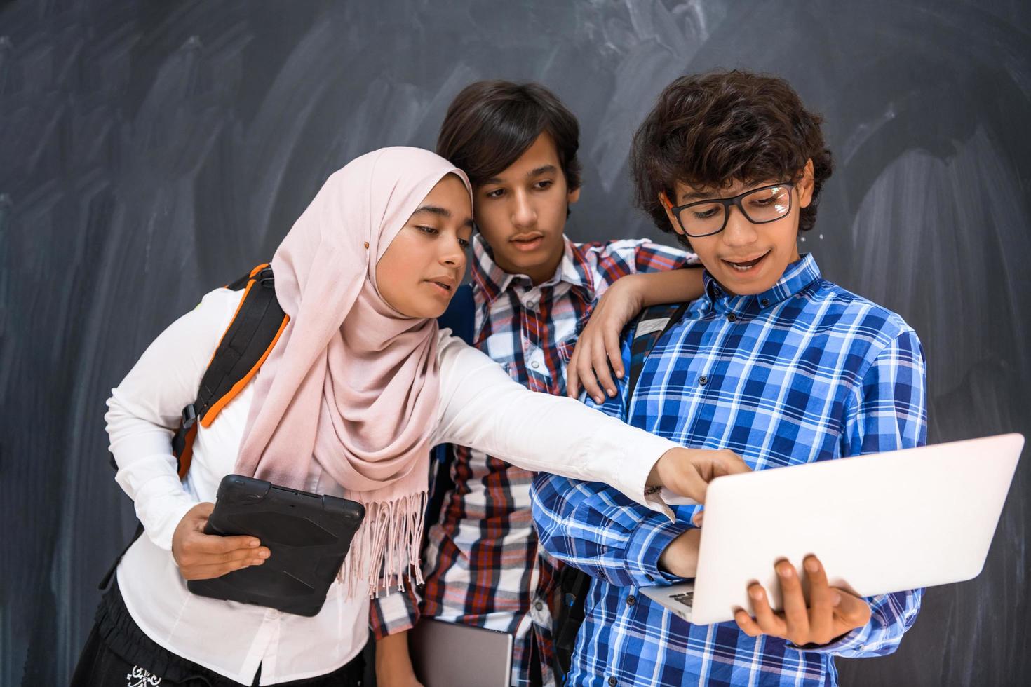 équipe d'adolescents arabes, groupe d'étudiants travaillant ensemble sur un ordinateur portable et une tablette concept d'éducation en classe en ligne photo