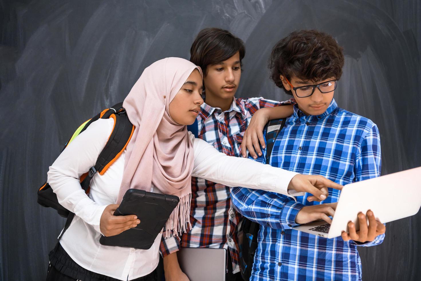 équipe d'adolescents arabes, groupe d'étudiants travaillant ensemble sur un ordinateur portable et une tablette concept d'éducation en classe en ligne photo