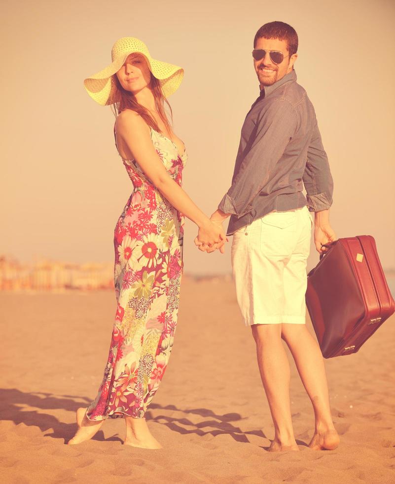 couple sur la plage avec sac de voyage photo