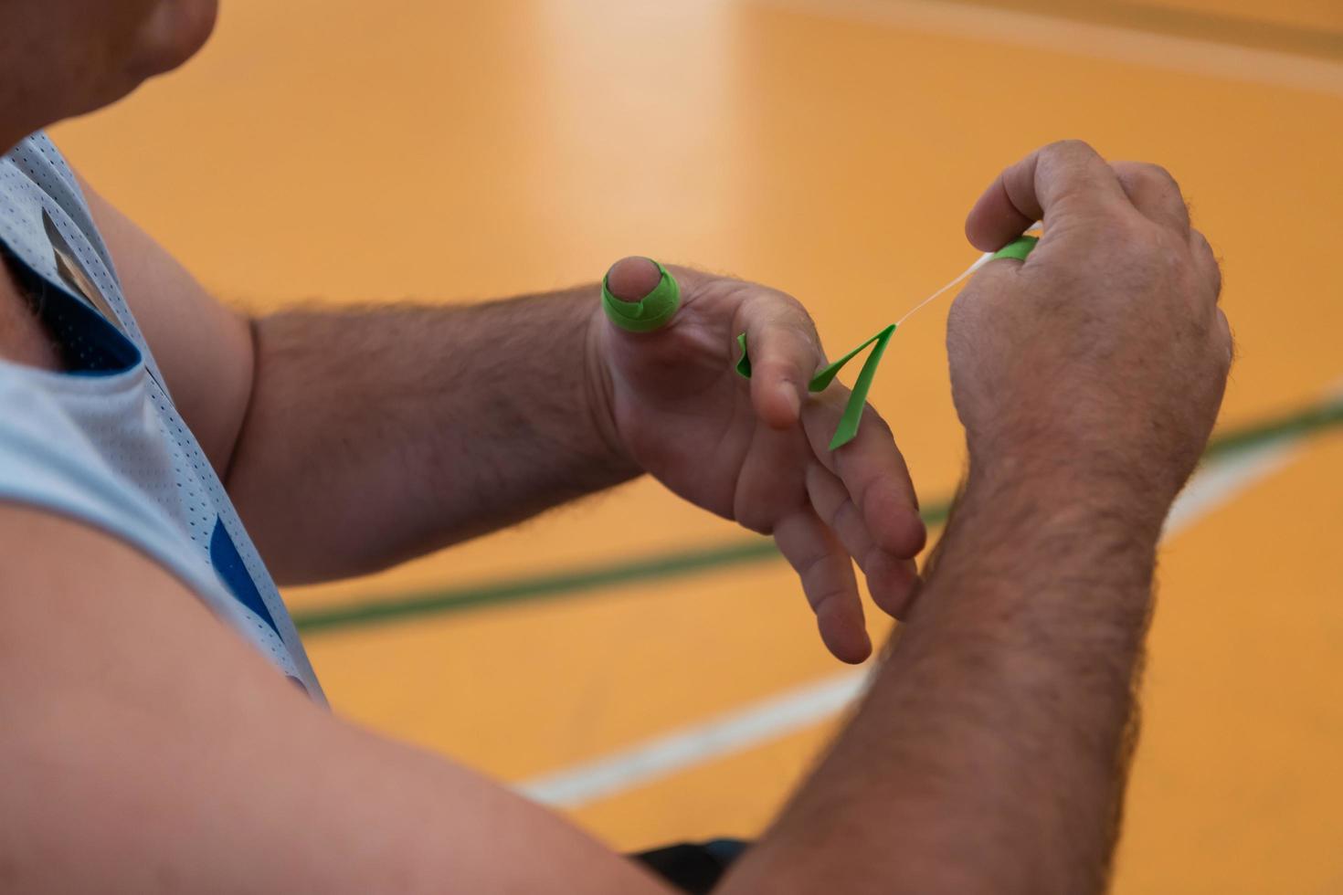 un basketteur handicapé met un corset et des bandages sur ses bras et ses doigts en vue d'un match dans l'arène photo